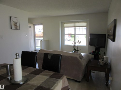 Bright living area featuring light-toned wood-finish flooring, a large window, and white walls - 64 Heatherglen Close, Spruce Grove, AB 
