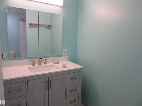 Bathroom vanity featuring a light gray shaker-style cabinet with brushed nickel hardware, a white countertop, and an integrated rectangular sink - 64 Heatherglen Close, Spruce Grove, AB 