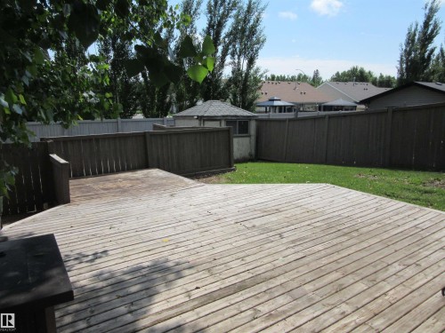 Expansive wood deck with a privacy fence, complemented by a manicured lawn area and an exterior storage shed - 64 Heatherglen Close, Spruce Grove, AB 