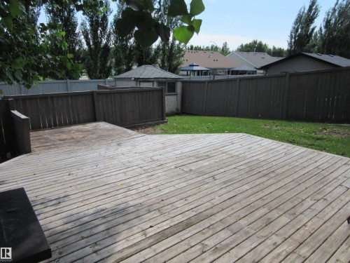 Expansive wood deck with a built-in bench, offering a spacious outdoor area - 64 Heatherglen Close, Spruce Grove, AB 