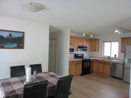 Open-concept kitchen and dining area featuring wood-finish flooring, ample cabinetry, and a full suite of appliances - 64 Heatherglen Close, Spruce Grove, AB 