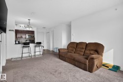 Open-concept living area with neutral carpeting and white walls - 