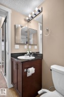 Bathroom vanity featuring a dark wood-finish cabinet with silver-tone hardware, a black stone countertop, and an undermount sink with a chrome faucet - 