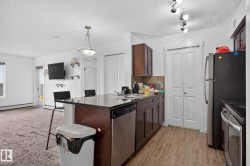 Kitchen area featuring wood-finish flooring, dark wood cabinetry, a stainless steel dishwasher, and a double basin sink - 