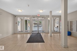 Spacious entry foyer featuring light-toned tile flooring, neutral wall paint, overhead flush-mount lighting, and floor-to-ceiling glass paneling at the entrance - 