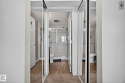 Bathroom featuring wood-finish flooring, a glass-enclosed shower, and a white toilet - 