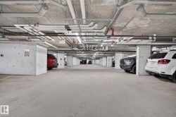 Underground parking garage featuring concrete flooring, concrete support columns, overhead piping, and ceiling-mounted lighting - 