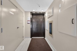 Hallway featuring a dark elevator door, recessed ceiling lighting, and light-toned wall panels - 