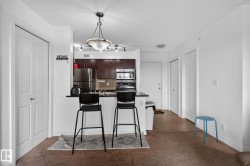 Open-concept kitchen featuring dark wood cabinetry, stainless steel appliances, and a breakfast bar with a dark countertop - 