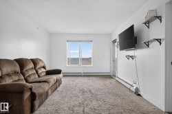 Bright living space featuring neutral carpeting, a large window, and a door providing exterior access - 