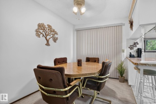 Dining area featuring a ceiling-mounted light fixture, vertical window blinds, and carpeted flooring - 4712 131 Avenue Nw, Edmonton, AB 