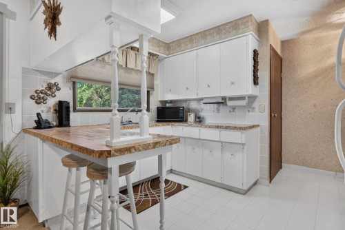 Kitchen featuring white cabinetry with decorative hardware, a built-in microwave, and a window above the sink - 4712 131 Avenue Nw, Edmonton, AB 