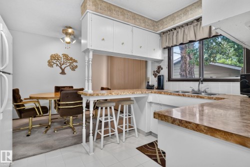 Kitchen with white cabinetry, brown-toned countertops, a double-basin sink, and a window above - 4712 131 Avenue Nw, Edmonton, AB 