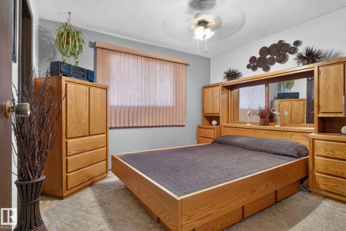 Bedroom featuring a built-in wood-finish bed frame with integrated storage and a mirrored headboard - 4712 131 Avenue Nw, Edmonton, AB 