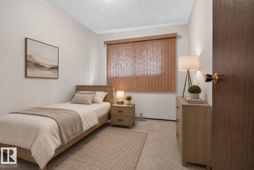 Carpeted room with a textured ceiling, featuring a vertical blind window treatment, a wood-finish bed frame, and a dark wood-grain interior door - 4712 131 Avenue Nw, Edmonton, AB 