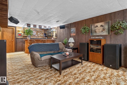 Recreation room featuring wood paneling, drop ceiling, and patterned carpet flooring - 4712 131 Avenue Nw, Edmonton, AB 