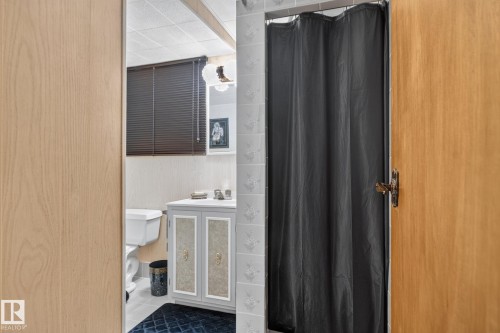 Bathroom featuring a vanity with cabinet storage, toilet, wall-mounted light fixture, and blinds - 4712 131 Avenue Nw, Edmonton, AB 