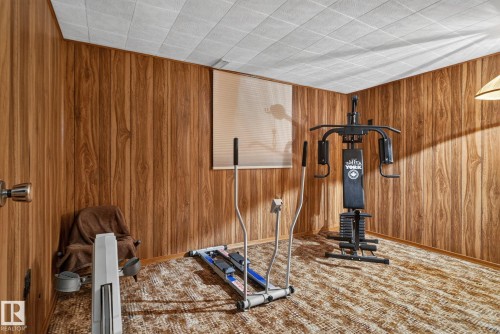 Room featuring wood-finish paneling walls and patterned carpeting - 4712 131 Avenue Nw, Edmonton, AB 