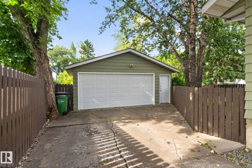 Detached garage with horizontal siding, a white overhead door, and a separate service door, accessible via a concrete driveway - 4712 131 Avenue Nw, Edmonton, AB 