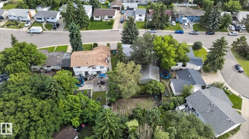 Aerial view showcasing a residential property with a brown shingle roof, mature trees, and a spacious backyard - 4712 131 Avenue Nw, Edmonton, AB 
