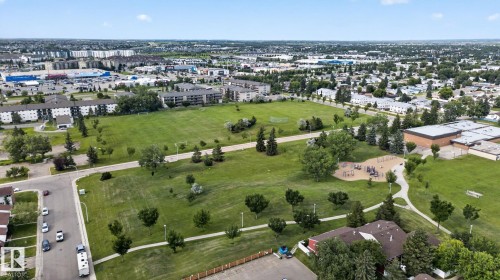 Expansive green space featuring a playground area, paved walking paths, and mature trees - 4712 131 Avenue Nw, Edmonton, AB 