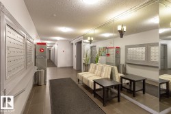 Building lobby featuring tile flooring, full-height mirrored wall, and recessed ceiling lighting - 