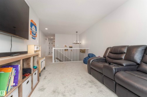 Carpeted upper level with vaulted ceiling, white walls, and a black wrought iron and white wood railing - 102 Horton Way, Ardrossan, AB 