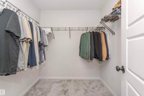 Walk-in closet featuring light gray carpeting, white walls, and wire shelving with hanging rods - 102 Horton Way, Ardrossan, AB 