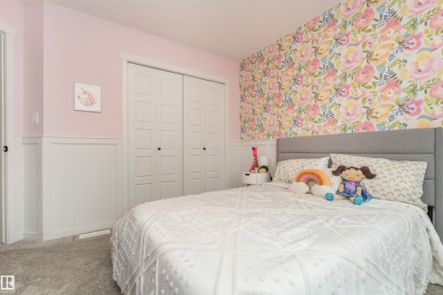 Bedroom featuring a floral accent wall, wainscoting, and carpet flooring - 102 Horton Way, Ardrossan, AB 