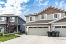 Contemporary duplex exterior featuring light gray siding, brown shake accents, and stone veneer details - 102 Horton Way, Ardrossan, AB 