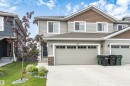 Two-story residence featuring light gray siding, brown shake accents, and a dual-car garage - 102 Horton Way, Ardrossan, AB 
