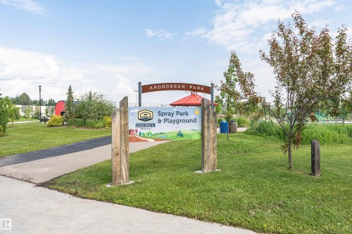 Ardrossan Park entrance featuring a prominent park sign, paved pathways, and mature trees - 102 Horton Way, Ardrossan, AB 