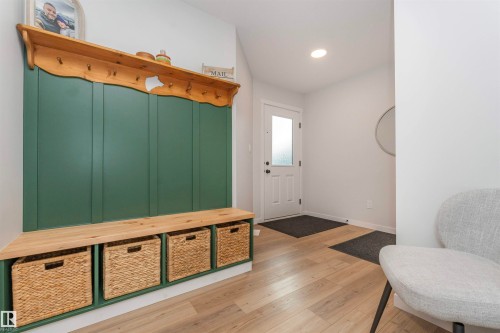 Entryway featuring a built-in bench with storage, wood-finish flooring, and white walls - 102 Horton Way, Ardrossan, AB 