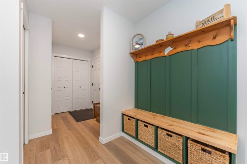 Built-in hall tree with a wood-finish bench, green paneling, and storage cubbies - 102 Horton Way, Ardrossan, AB 