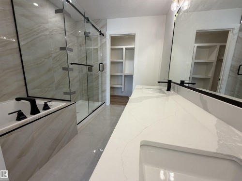 Dual vanity with integrated sinks and white countertops, featuring matte black faucets and a large wall-mounted mirror - 115 Pierwyck Loop, Spruce Grove, AB 