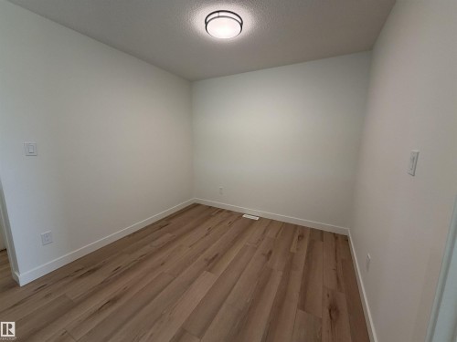 Light wood-finish flooring, crisp white baseboards, and a contemporary flush-mount ceiling light fixture - 115 Pierwyck Loop, Spruce Grove, AB 