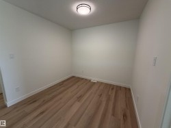 Light wood-finish flooring, crisp white baseboards, and a contemporary flush-mount ceiling light fixture - 