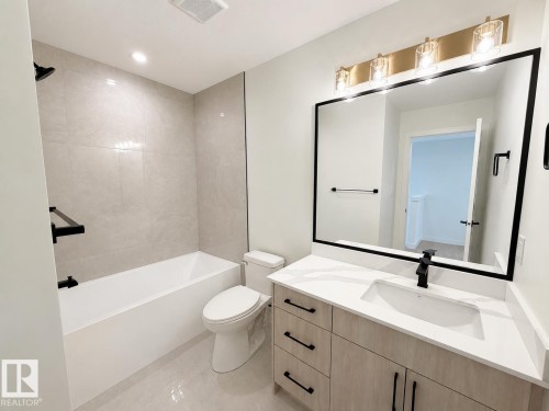 Bathroom featuring a light wood-finish vanity with a quartz countertop, an integrated rectangular sink, and a matte black faucet - 115 Pierwyck Loop, Spruce Grove, AB 