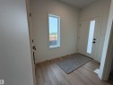 Entryway featuring a white door with vertical glass insert, black hardware, wood-finish flooring, and a tall vertical window - 115 Pierwyck Loop, Spruce Grove, AB 
