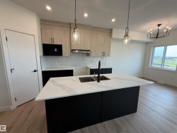 Kitchen featuring a large island with an undermount double sink, quartz countertop, and pendant lighting - 