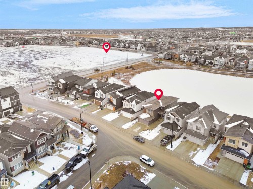 Residential neighborhood featuring a mix of detached homes, a central street, and a large body of water - 19066 20A Avenue, Edmonton, AB 
