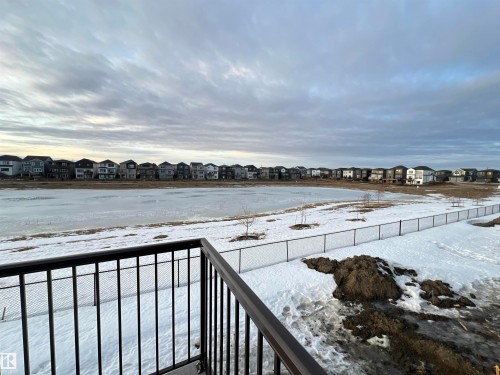 Black metal balcony railing overlooking a snow-covered landscape with a frozen body of water - 19066 20A Avenue, Edmonton, AB 