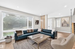 Spacious living area featuring large windows with blinds, recessed lighting, wood-finish flooring, a decorative wood slat partition, and painted walls - 