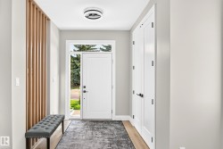 Foyer featuring a contemporary wood slat accent wall, a white entry door with frosted sidelight and transom, and wood-finish flooring - 