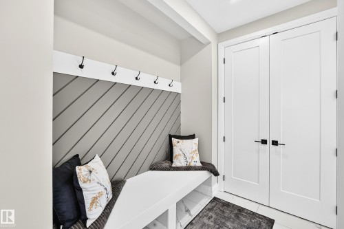 Built-in mudroom bench featuring a slatted accent wall and black coat hooks - 12631 52 Avenue, Edmonton, AB 