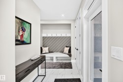 Entryway featuring white tile flooring, a built-in bench with storage, and a paneled accent wall with coat hooks - 
