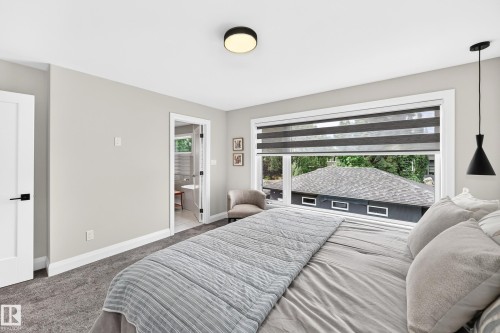 Bedroom featuring neutral-toned carpet, a large window with privacy blinds, and a modern pendant light fixture - 12631 52 Avenue, Edmonton, AB 