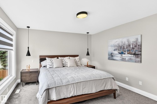 Bedroom featuring a large window with privacy blinds, dual pendant lighting, a ceiling-mounted light fixture, and carpet flooring - 12631 52 Avenue, Edmonton, AB 