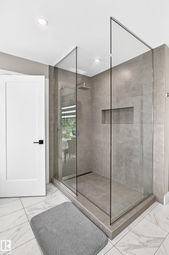 Modern walk-in shower featuring clear glass panels, a rainfall showerhead, and a recessed niche - 12631 52 Avenue, Edmonton, AB 