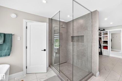 Sleek glass-enclosed shower with full-height tile surround and integrated shower niche - 12631 52 Avenue, Edmonton, AB 